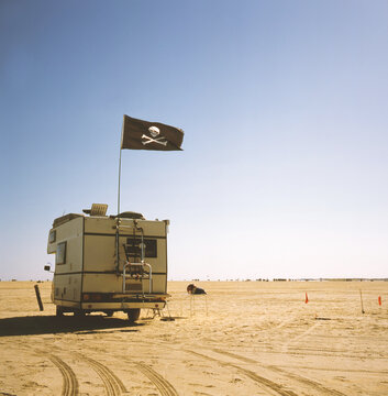 Camper with pirate flag, parked on the beach in Denmark