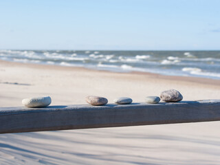 Stones on wooden beam on clear sky and beach background