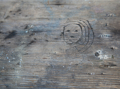 Face of a girl etched into a wooden picnic table