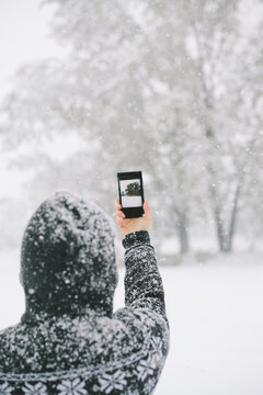 Woman taking a photo of snowy trees