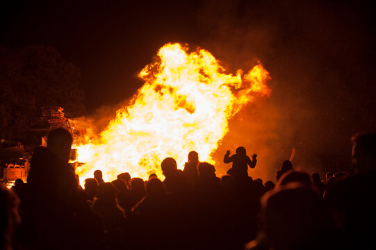 people in silhouette watching a public bonfire
