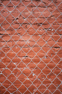 Chain-link fence in front of painted brick wall