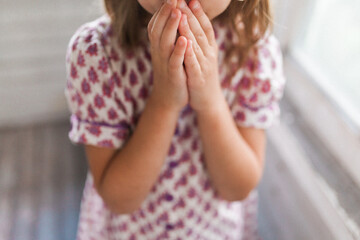 Girl holding hands to mouth, facing forward