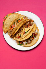 Mexican hard-shell tacos with meat and fresh sauce on pink background