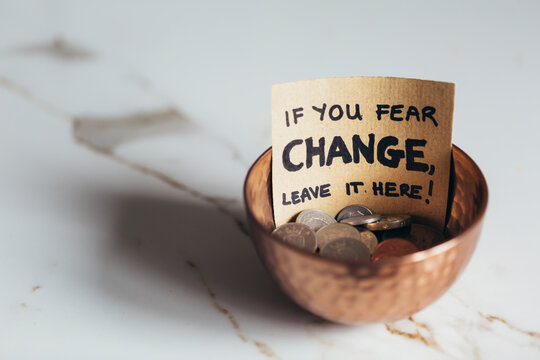 Copper bowl with coins with sign "If you fear change, leave it here"