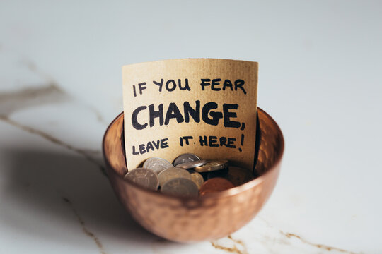 Copper bowl with coins with sign "If you fear change, leave it here"