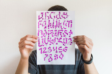 Young man holding artwork calligraphy design in front of his face