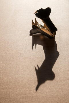 Staple remover casting a long shadow on a desk