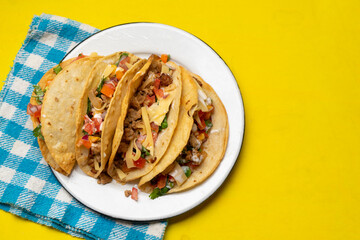 Mexican hard-shell tacos with meat and fresh sauce on yellow background