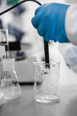 Flask and pipette in scientist hand with dropping chemical liquid to test tubes, science and medical research and development concept