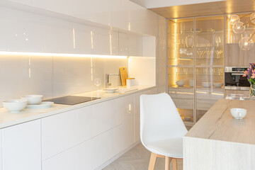 luxury interior design of modern trendy snow white kitchen in minimalistic style with island and two bar stools. huge windows to the floor and a glass rack for dishes