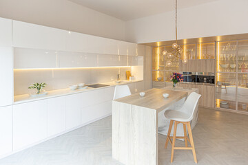 luxury interior design of modern trendy snow white kitchen in minimalistic style with island and two bar stools. huge windows to the floor and a glass rack for dishes