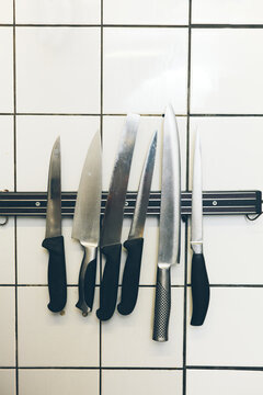 Chef's knives hanging on the wall, being held by a magnet
