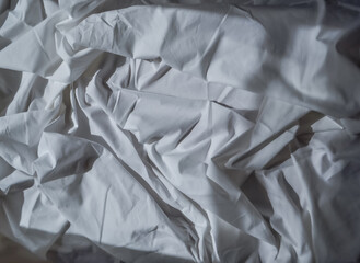 beautiful white fabric wrinkled sheet drape with folds in the light of the sun with shadows and...