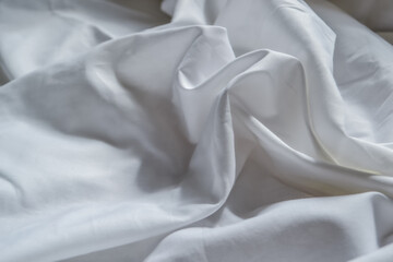 beautiful white wrinkled fabric  sheet drape with folds in the light of the sun with shadows and reflections
