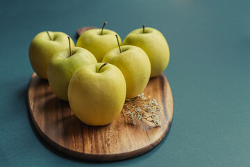 yellow golden delicious apples on green table, wooden cutting board 