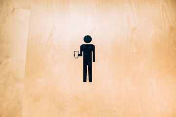 The icon to a men's bathroom, holding a beverage