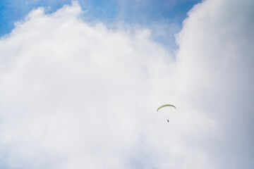 Paragliding in the cloudy blue sky.