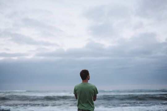 Man with looking out at ocean thinking - alone