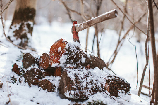 Axe stack in stacked tree trunks in a snowy forest.