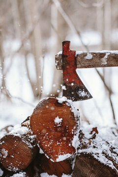 Axe stack in stacked tree trunks in a snowy forest.