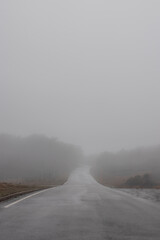 Empty mountain road in thick fog