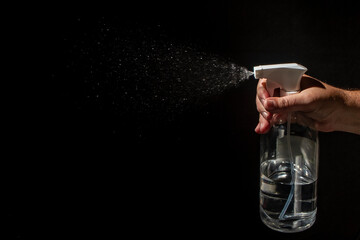 On a black background, male hand open a spray