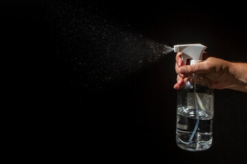 On a black background, male hand open a spray