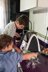 Two children preparing pancakes with a kitchen robot.