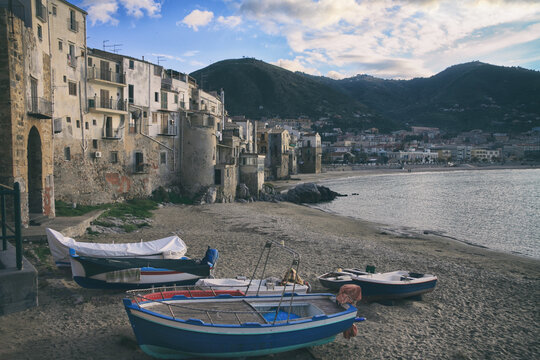 Boats on a sandy shore nearby old Sicilian houses