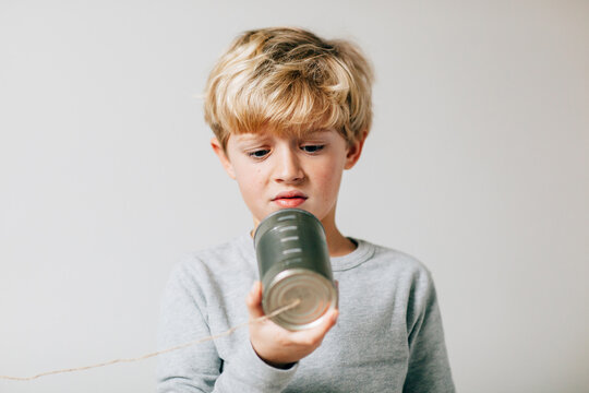 dissatisfied boy looking at his lame tin can phone