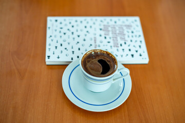 An closed book and cup of Turkish coffee on a brown wooden table