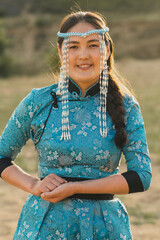 Mongolian woman wears national costume in a desert at sunset.