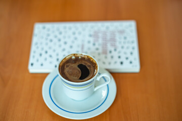An closed book and cup of Turkish coffee on a brown wooden table