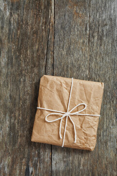 Package wrapped in wrinkled brown paper lying on weathered wood