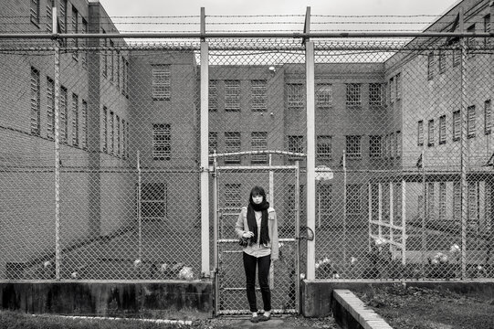 Decay Tourism: Young Woman with Camera Outside Barbed Wire Facil
