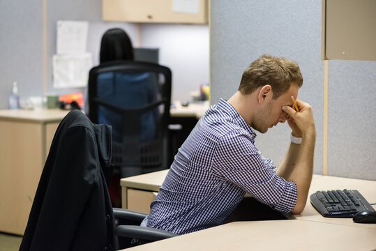 Man in cubicle rubbing his temples