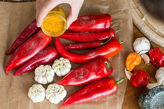 Hand sprinkling turmeric on peppers and garlic