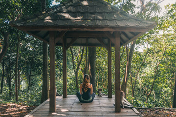 Mulher sentada em templo na Mokey Forest, em Ubud, Bali, Indonésia.