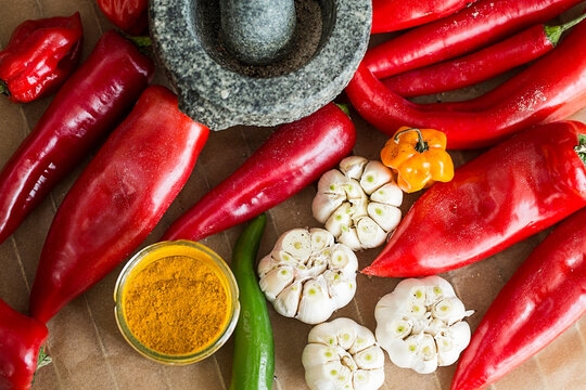 Peppers, garlic and chilies next to mortar and pestle