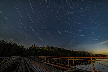 Stary most kolejowy nocą i star trails wokół gwiazdy Polarnej