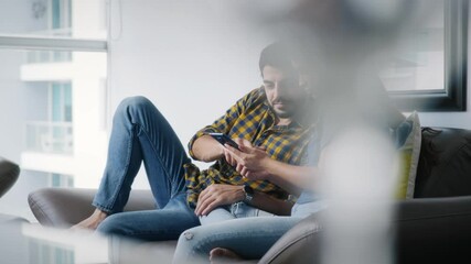 Young couple using cell phone for internet and social media. Happy man and woman holding smartphone with for website. Husband and wife watching video on mobile telephone - Powered by Adobe