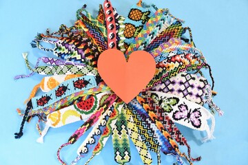 Red heart in the middle of circle of many multi-colored woven DIY friendship bracelets handmade of...