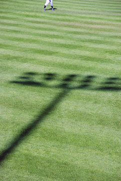 Shadow of baseball stadium lights on field with outfielder