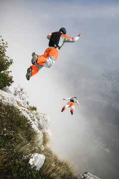 Two BASE jumpers exiting from a cliff in Italy