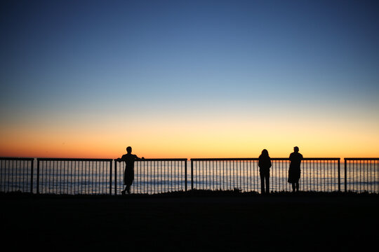 Three silhouettes watching the sunset in Santa Cruz