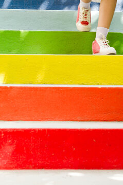 Anonymous teenage girl walking down colorful staircase