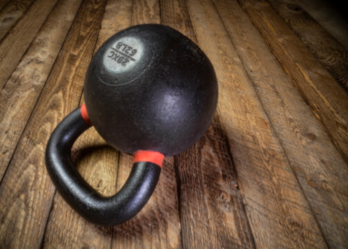 heavy iron kettlebell on a rustic wood background - fitness concept,  soft focus black and white image shot with lensless pinhole camera