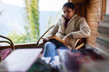 Woman reading a book by the glass window