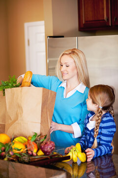 Family: Girl Helps Mother Put Away Groceries